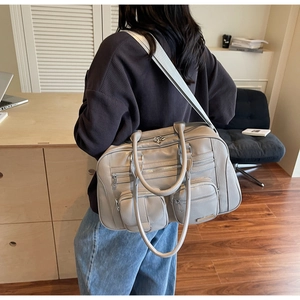 Dettaglio della borsa a spalla in tela taupe con tre tasche frontali e tracolla