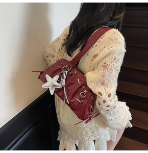 Detail shot of a wine red patent leather shoulder bag featuring trendy pleats and a silver star charm.