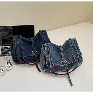 Détail de sacs en denim bleu avec anses en cuir rouge et boucles en métal argenté
