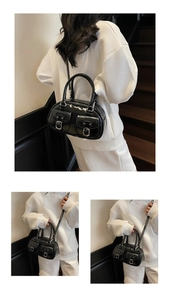 Detail of black glossy faux leather handbag with silver buckles and adjustable shoulder strap