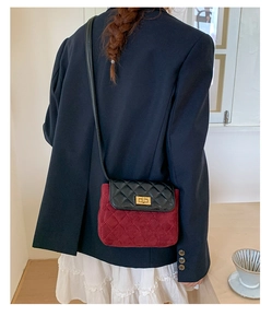 Detail of burgundy suede crossbody bag with black quilted flap and gold clasp on model