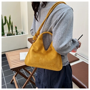 Detail of mustard yellow suede dumpling bag with adjustable knotted shoulder strap
