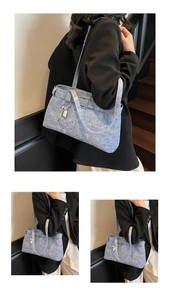 Close-up of blue denim texture tote bag with stylish buckle straps and silver key charms