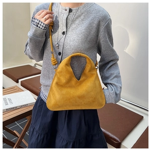 Detail of bright yellow suede shoulder bag with V-shaped handle and knot strap