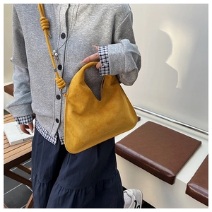 Detail of yellow suede dumpling bag featuring unique knotted shoulder strap and matte texture