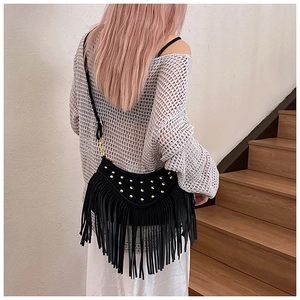 Macro shot of black suede crossbody bag with gold studs and long stylish tassels