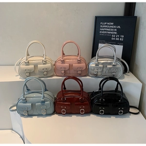 Six glossy leather Boston bags in various colors on white podium with metal buckles