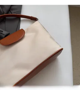 Close-up of contrast oxford tote bag showing cream fabric texture and brown leather flap