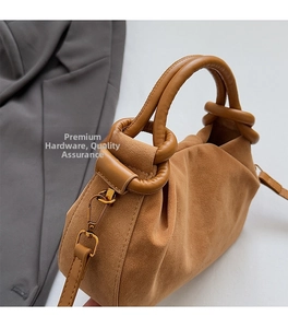 Detail van de geplooide cloud-bag in karamelbruin met geknoopte handgreep en gouden haak