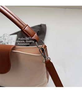 Detail of silver metal hook and leather strap on a beige Oxford fabric tote bag