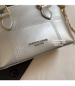 Detail der silbernen Ledertasche mit feiner Textur und goldenem Metallring-Beschlag