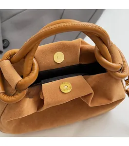 Detail van de bruine suède cloud-tas met magneetsluiting en geknoopte handgreeptextuur