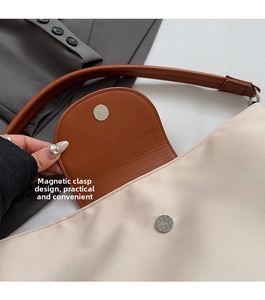 Detail of silver magnetic buckle closure on a beige nylon and brown leather tote bag