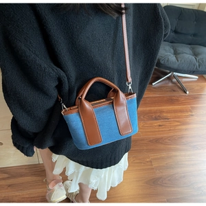 Close-up of mini denim and brown leather crossbody bag styled with a white pleated skirt