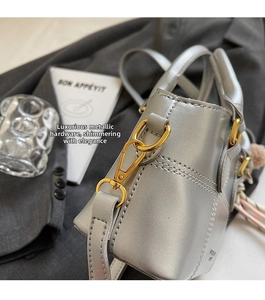 Nahaufnahme der silbernen Handtasche mit goldener Hardware und elegantem Seidenschal-Detail