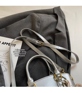 Nahaufnahme der silbernen Lederhandtasche mit verstellbarem Riemen und Goldbeschlägen