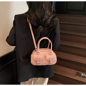 Detail of a pink glossy leather shoulder bag featuring dual pockets and silver hardware