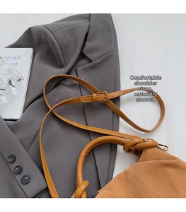 Detail van de bruine suède cloud bag met verstelbare riem en een handvat met knoopdetail
