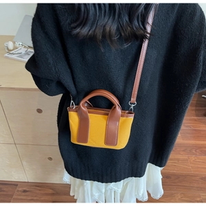 Detail of mini canvas crossbody bag in yellow and brown leather on a model