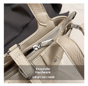 Vue détaillée de la fermeture éclair argentée et du cuir grainé du sac beige