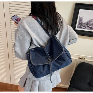 Detail of vintage dark blue denim shoulder bag featuring buckle flap and metal hardware
