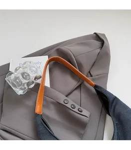 Detail of contrasting brown leather strap and navy blue canvas on a waterproof shoulder bag