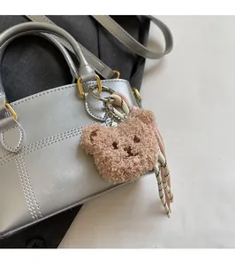 Nahaufnahme eines braunen Plüschbär-Anhängers mit Kordel an einer silbernen Tasche
