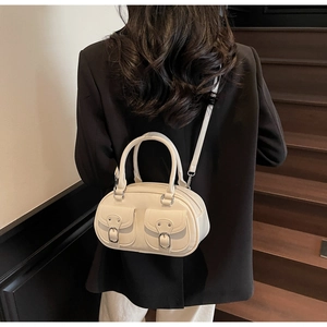 Detail view of cream shoulder bag with double pockets and silver metal buckles
