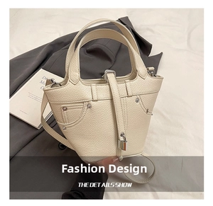 Détail du sac seau en cuir crème motif litchi avec serrure métallique et rivets décoratifs