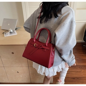 Detail of burgundy bridal handbag with gold metal buckles and adjustable shoulder strap