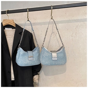 Detail of light blue crescent denim bags with glittering sequins and chain straps