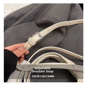 Détail de la bandoulière réglable en cuir avec boucle argentée sur un sac seau élégant