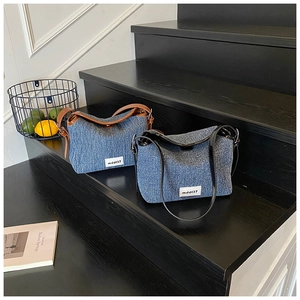 Detail of trendy denim shoulder bags with leather straps on a modern wooden staircase