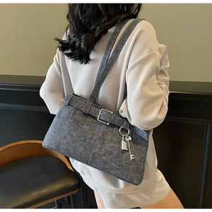 Detail of grey denim tote bag with silver metal buckles and key lock pendant on model