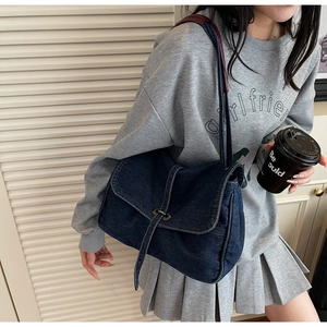 Détail du sac bandoulière en denim bleu avec boucle en métal et texture denim