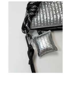 Detail of silver metallic quilted bag featuring woven cord strap and puffer pendant