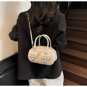 Fashionable ivory retro shoulder bag with double buckle pockets shown on a model