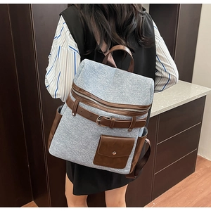 Detail of vintage denim backpack featuring leather buckle accents and brown trim on model