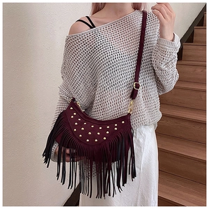 Detail of burgundy crescent bag with golden studs and long bohemian tassels