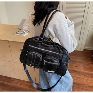 Dettaglio borsa in pelle PU nera lucida con design multitasca e cerniere metalliche