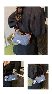 Detail of blue denim shoulder bag featuring brown leather trim and a cute teddy bear charm