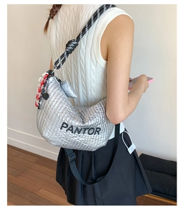 Detail of silver quilted crescent bag with PANTOR embroidery and braided strap