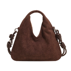 Detail of dark brown suede dumpling bag featuring woven knot accents and silver hardware