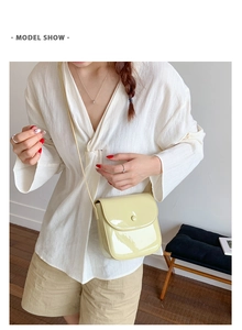 Mannequin portant un sac besace minimaliste en cuir verni jaune pâle avec bandoulière fine