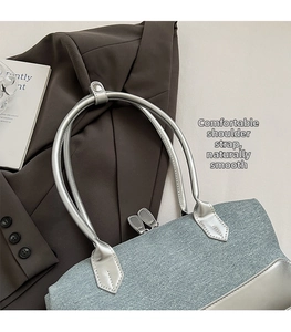 Detailed close-up of blue textured fabric handbag with dual silver zippers and long handles