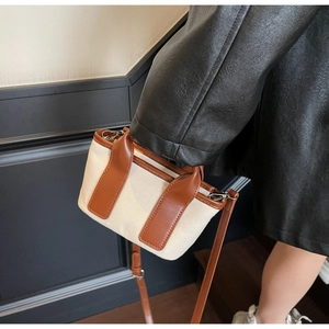 Dettaglio di un elegante secchiello in tela a contrasto con manici in pelle marrone chic