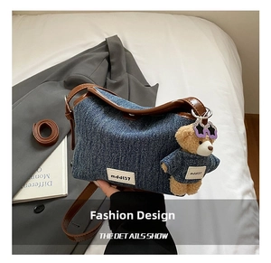 Detail of denim crossbody bag with brown leather trim and cute teddy bear charm