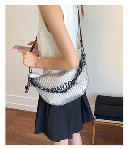 Detail of silver metallic crescent bag with woven texture and black and white strap