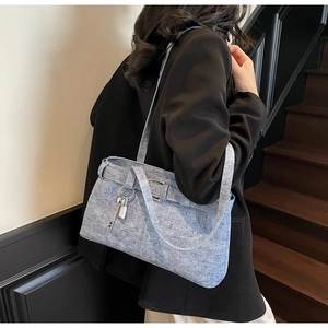 Detail view of light blue denim hobo bag with silver buckle and lock charm on a model