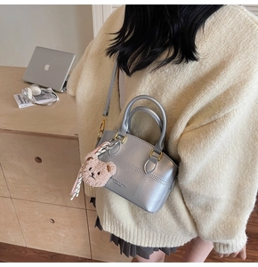 Silver quilted mini bag with brown teddy bear charm shown in a cozy lifestyle setting